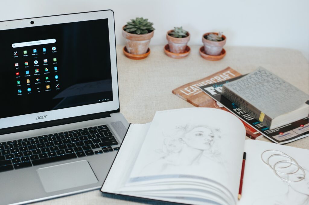 This image shows the Acer Laptop with a notebook and with pen in the table.